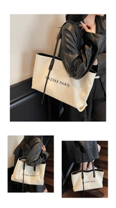 Gros plan sur la bandoulière en cuir noir et le logo de ce grand sac cabas beige