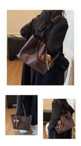 Detail view of a large brown leather tote bag with stylish charms and shoulder straps