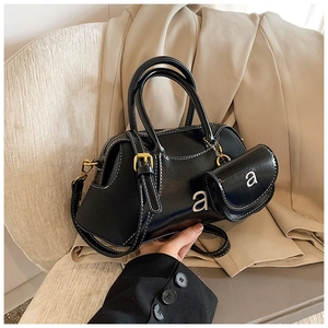 Detail view of black glossy Boston bag featuring contrast white stitching and mini coin purse
