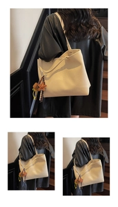 Close-up of cream leather tote with lychee texture and brown star tassel on wooden stairs
