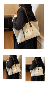 Détail du sac cabas en toile blanche avec anses marron et texte imprimé de style Paris
