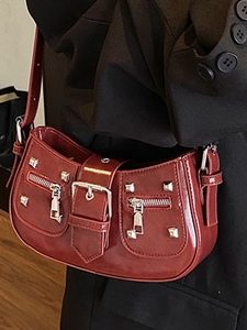 Burgundy rivet square handbag with metallic buckle and shoulder strap worn with black suit