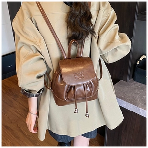 Detail of vintage brown leather backpack with drawstring closure and metal ball charms