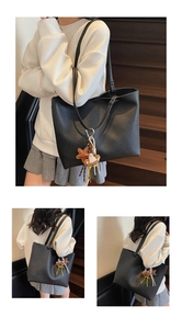 Detail view of large black lychee pattern leather tote bag with cute charms on straps
