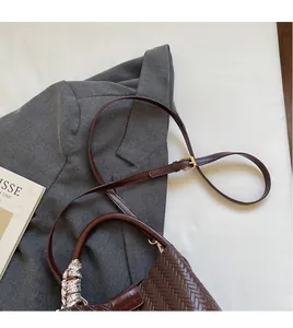 Détail du sac seau marron en cuir tressé avec foulard décoratif et boucle dorée
