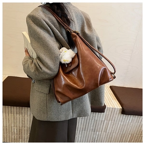 Détail d'un sac hobo marron vintage avec bandoulière réglable et breloque lapin en peluche