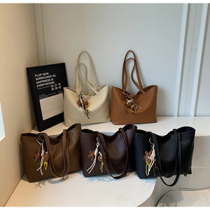 Detailed view of large tote bags in five colors with cute bear charms on a white stand