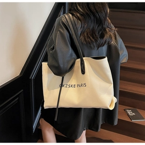 Vue détaillée du grand sac cabas en toile avec anses noires et lettrage de la marque