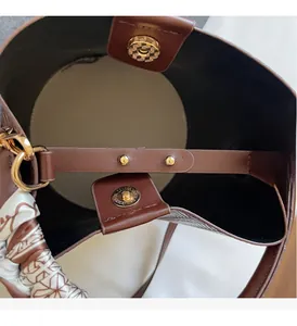 Détails du sac seau en cuir marron avec boucle dorée et foulard en soie élégant