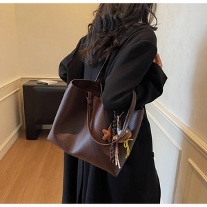 Detail of deep brown lychee grain leather tote bag with cute bear and star charms