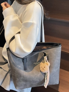 Dark grey minimalist tote bag for women with plush bear charm on stylish wooden stairs