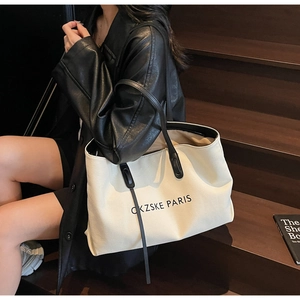 Gros plan détaillé du grand sac cabas en toile avec anses en cuir noir sur un escalier