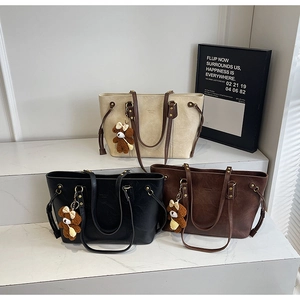 Trois sacs cabas minimalistes en cuir PU avec charm d'ours sur des marches blanches