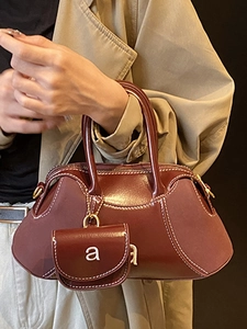 Burgundy red leather shoulder bag with white contrast stitching and a small letter charm