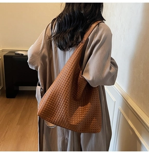 Texture détaillée du sac hobo tressé marron porté par un mannequin en décor épuré