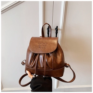 Detailed macro view of dark brown faux leather texture and metallic drawstring on small backpack