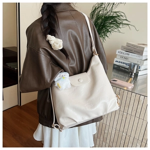 Détail d'un grand sac hobo crème en cuir souple avec un charmant pendentif chien peluche