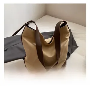 Detail shot of a large hobo shoulder bag featuring cream canvas and brown leather trim