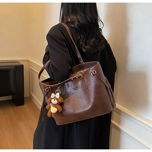Détail d'un grand sac cabas en similicuir avec logo et breloque ours en peluche mignon