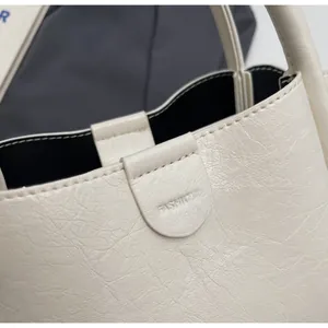 Close-up of lychee grain leather texture and Fashion embossed metal buckle on cream handbag