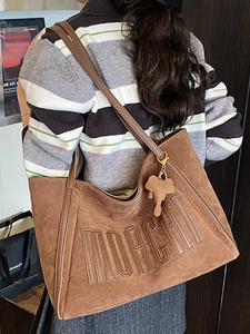 Brown suede large tote bag with MORCHI embroidery and elephant charm on a model's shoulder