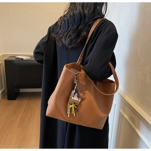 Close-up of brown litchi grain tote bag with a cute plush bear and star charm