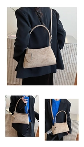 Detail view of beige suede baguette bag with a matching mini pouch and slim shoulder strap