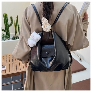 Vue arrière du mannequin portant un sac à dos hobo noir brillant avec porte-clé ours blanc