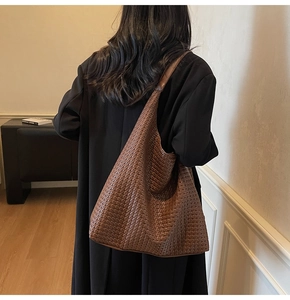 Gros plan du grand sac à bandoulière tressé marron avec texture cuir et large bandoulière