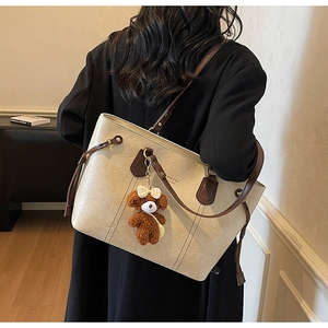 Détail du grand sac cabas en PU crème avec un pendentif ours et fines lanières