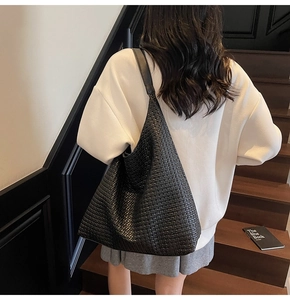 Gros plan du grand sac hobo noir tressé montrant sa texture souple et sa fabrication
