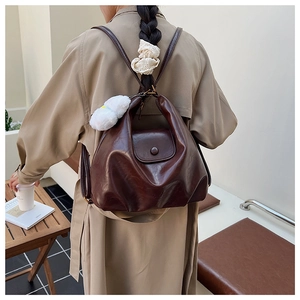 Détail du sac à dos en cuir marron foncé avec texture souple et pendentif nuage en peluche