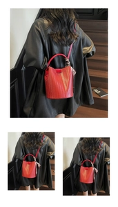 Détail du sac seau rouge tressé avec foulard floral élégant et fine bandoulière en cuir