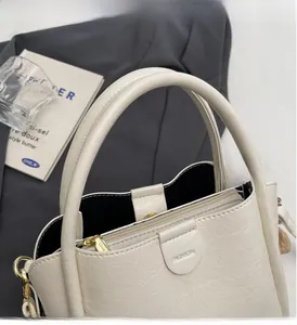 Detailed close-up of beige lychee grain leather handbag showing gold hardware and inner lining