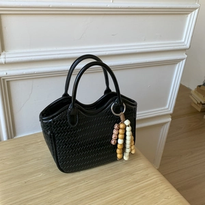 Vue de dessus d'un sac à main tissé noir avec gland en perles sur bureau en bois
