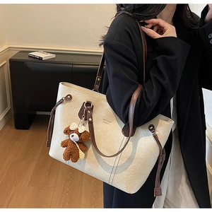 Vue détaillée du grand sac cabas en PU crème avec anses marron et charm ours mignon