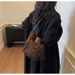 Detail view of a vintage bohemian brown suede bucket bag with long fringe and metal clasp