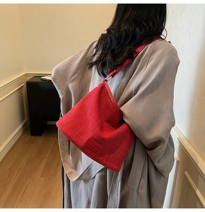 Dettaglio della borsa a secchiello rossa in tessuto abbinata a un cappotto grigio