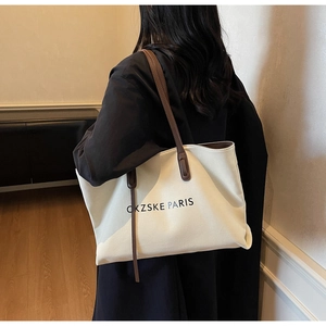 Détail du sac cabas en toile avec lanières en cuir marron et texte PARIS à l'épaule