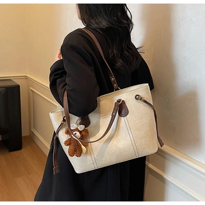 Détail du sac cabas minimaliste en PU crème avec anses marron et breloque ours en peluche
