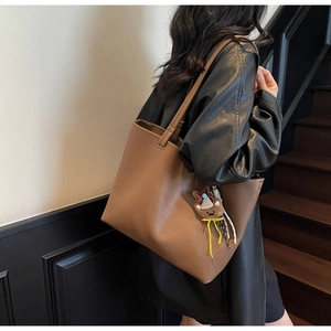 Detail of warm brown lychee texture tote bag with cute bear charm worn by a model