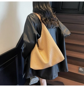 Détail macro de la texture tressée en cuir sur un grand sac à bandoulière hobo marron