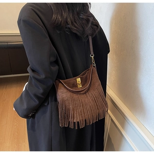 Detail of bohemian brown suede crossbody bag showing fringe texture and gold twist lock