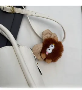 Detail of creative plush charm with long brown fur and beige ears on a white bag strap