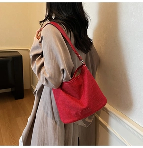 Dettaglio di una borsa tote rossa intrecciata indossata con un trench beige chiaro