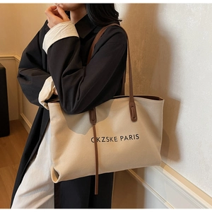 Détail du sac fourre-tout en toile crème avec bandoulières en cuir marron et logo Paris