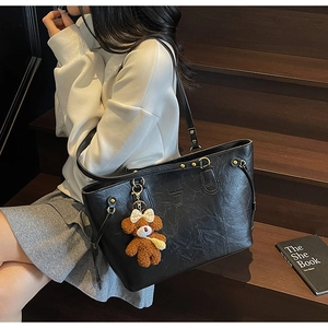Détail du sac cabas en PU noir avec texture froissée et breloque ours en peluche marron