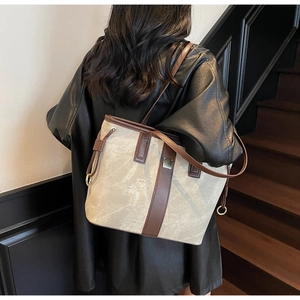 Détail d'un grand sac fourre-tout crème avec bordure en cuir marron foncé sur modèle