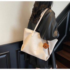 Detail of off-white tote bag with pleated leather texture and a cute teddy dog charm