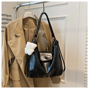 Détail du sac cabas noir brillant avec boucle décorative et breloque d'ours blanc
